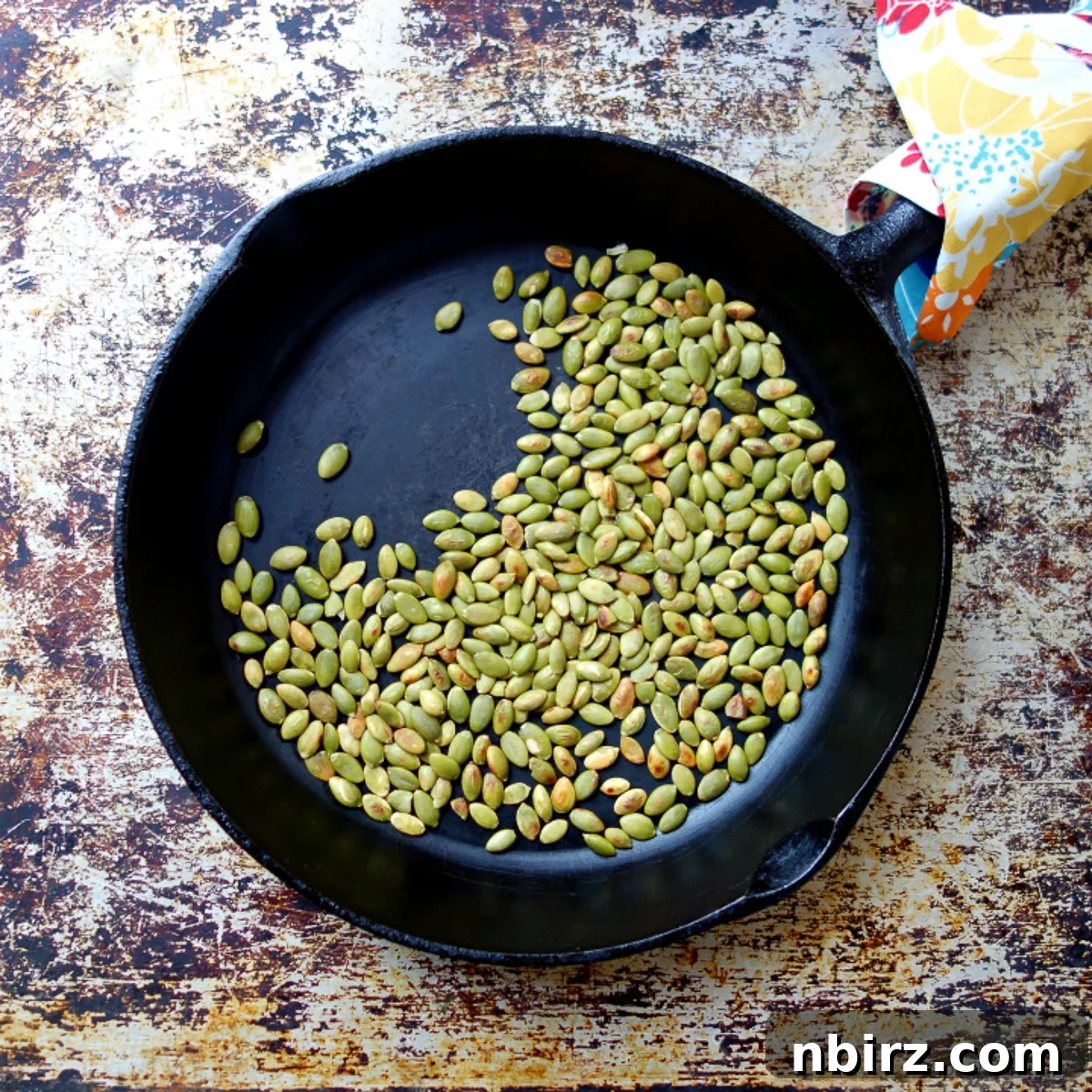 Simple Three Ingredient Vegan Grain Free Almond Flour Granola Bars 5 Toasted pepitas in a cast iron skillet, emitting a delicious aroma