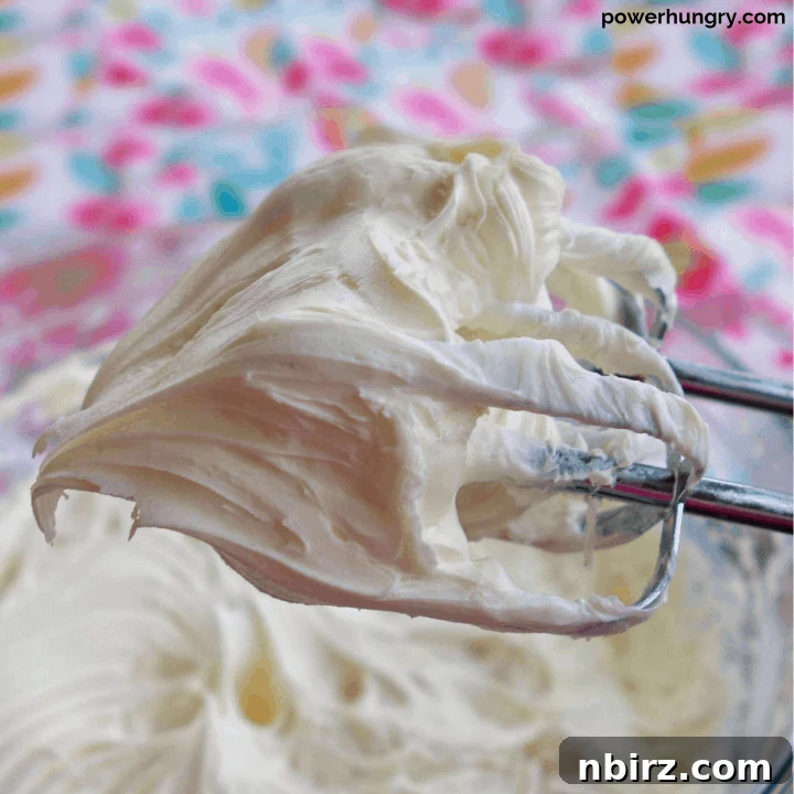 Silky Smooth Vegan Vanilla Buttercream Without Cornstarch 2 Close-up of electric beaters covered in swirls of fluffy vegan vanilla buttercream frosting, ready to be spread on desserts.