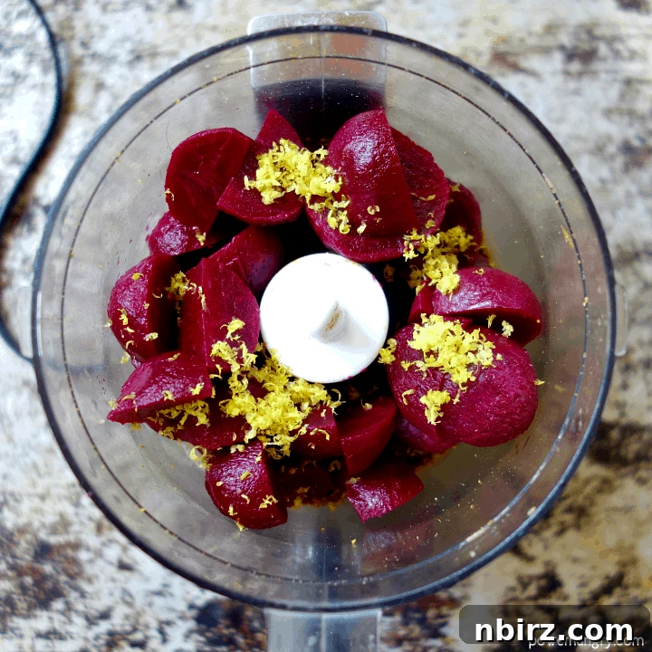 Velvety Beet and Toasted Pepita Dip 8 An overhead shot depicting vibrant baby beets and bright yellow lemon zest being added to the food processor bowl, joining the finely ground pepita mixture, ready for the final blending stage.