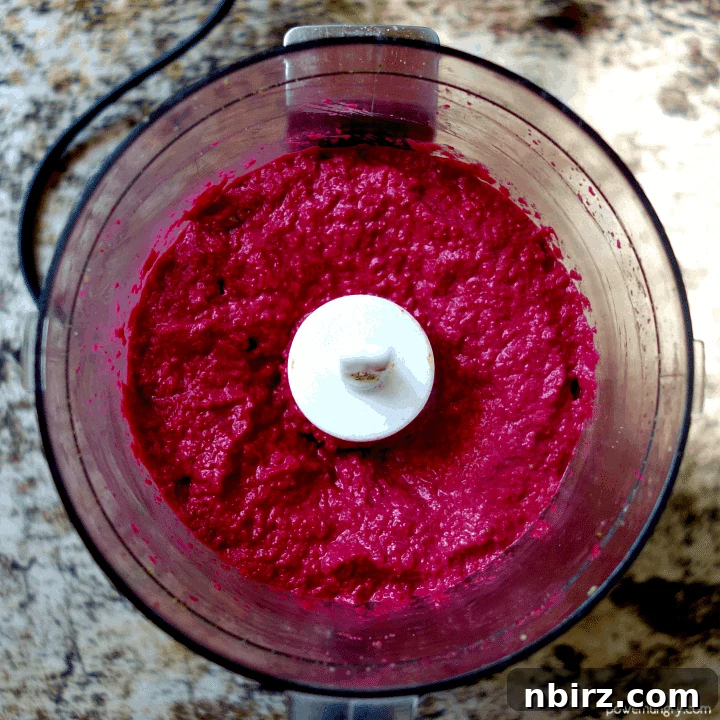 Velvety Beet and Toasted Pepita Dip 9 A close-up view of the perfectly pureed, smooth, and creamy beet and pepita dip inside the food processor bowl, showcasing its rich, even magenta color.