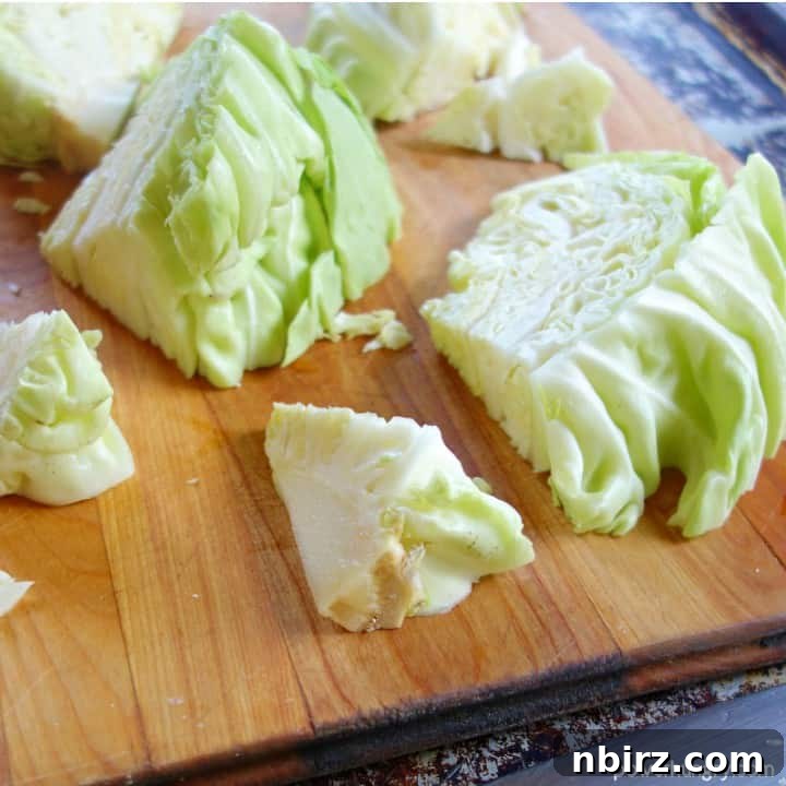 Caboodles: One-Ingredient Vegan Keto Steamed Cabbage Noodles 5 Cabbage pieces on a wooden cutting board with a knife expertly cutting out the tough inner cores, a crucial step for preparing tender cabbage noodles.