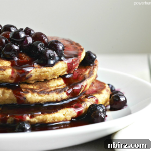 A vibrant, short stack of 3-ingredient vegan chickpea flour pancakes on a clean white plate, garnished with fresh berries.