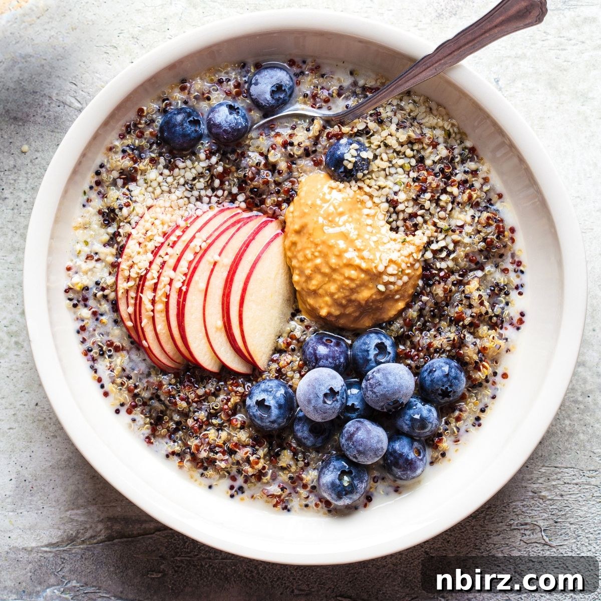 overhead shot of creamy quinoa porridge in a white bowl, ready to be topped