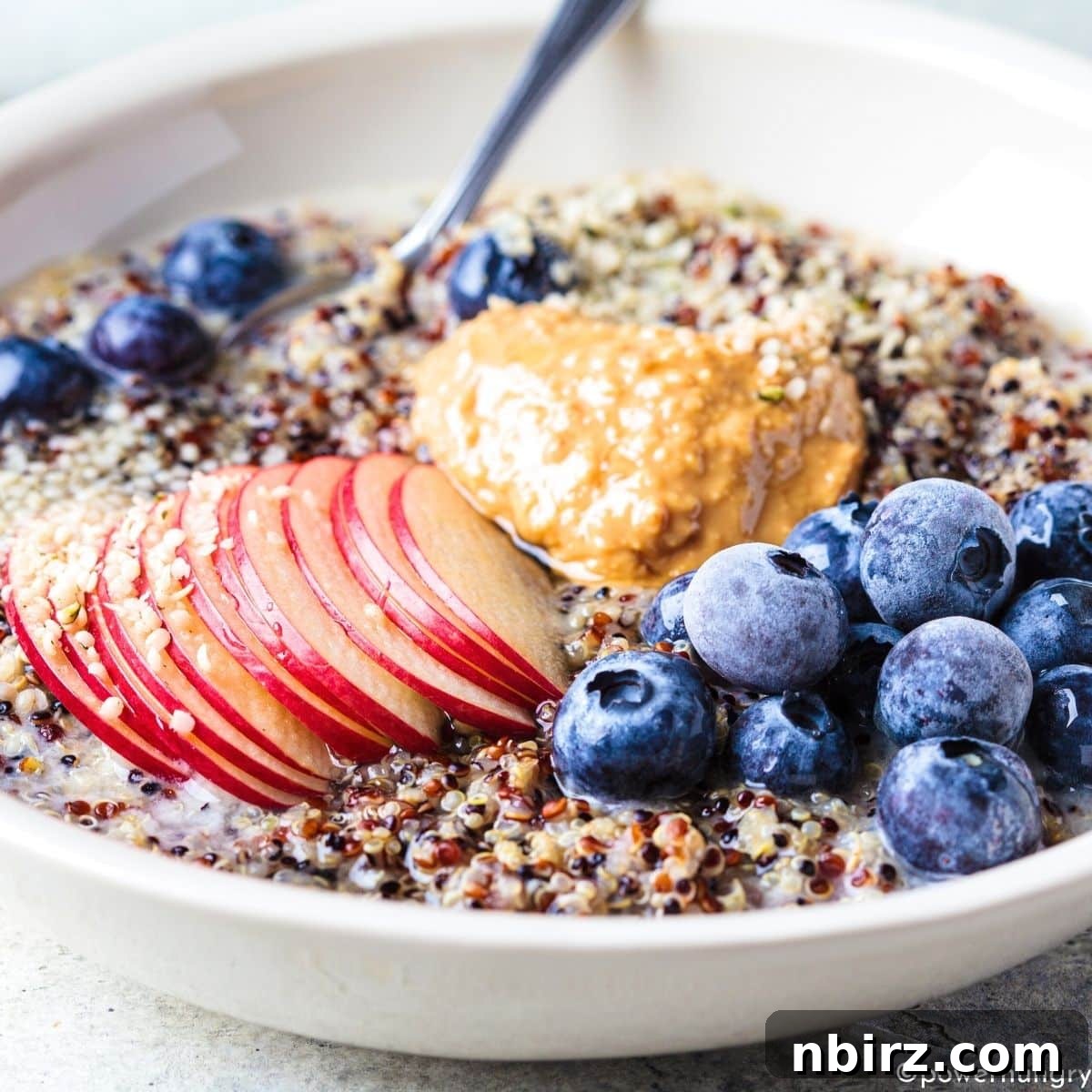 a bowl of quinoa porridge artfully arranged with various colorful toppings