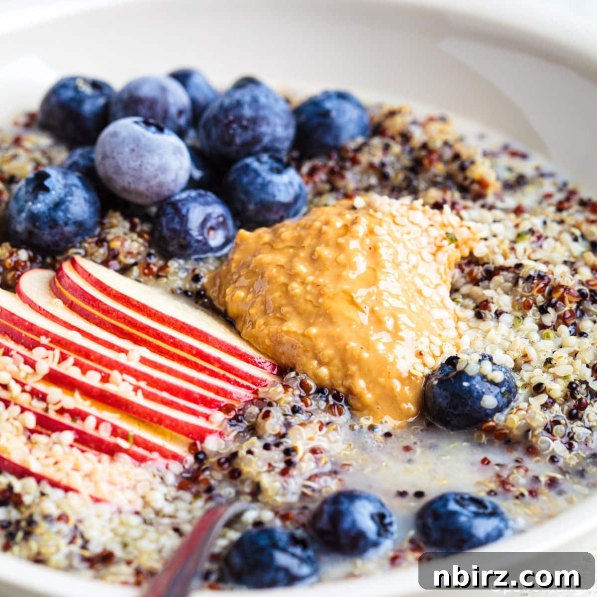quinoa porridge breakfast bowl, beautifully topped with fresh nut butter and a variety of colorful fruits
