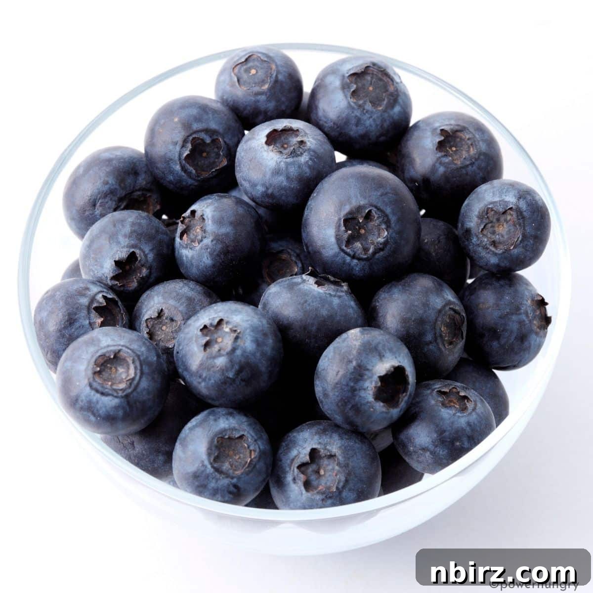 A small glass dish filled with fresh, vibrant blueberries.