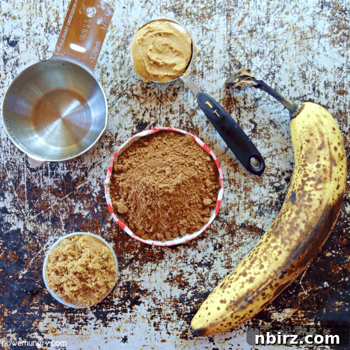 Wholesome Vegan Gluten Free Chocolate Banana Oat Cookies 4 Ingredients for healthy chocolate banana oat cookies laid out, including bananas, cocoa powder, oats, and nut butter.