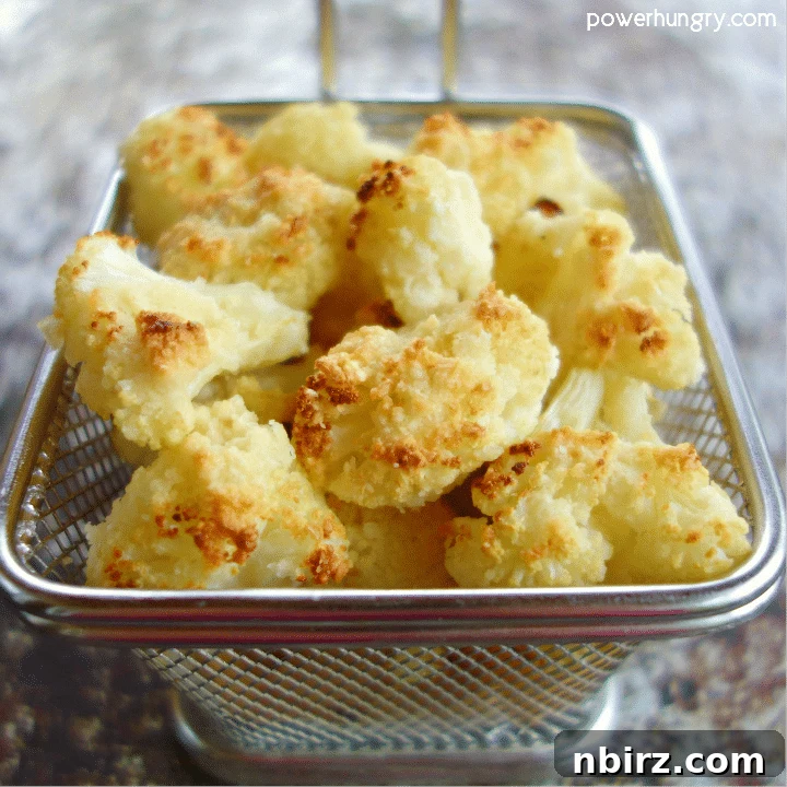 A small rustic basket filled with golden-brown almond flour cauliflower popcorn, garnished with fresh herbs, showcasing its perfect texture.