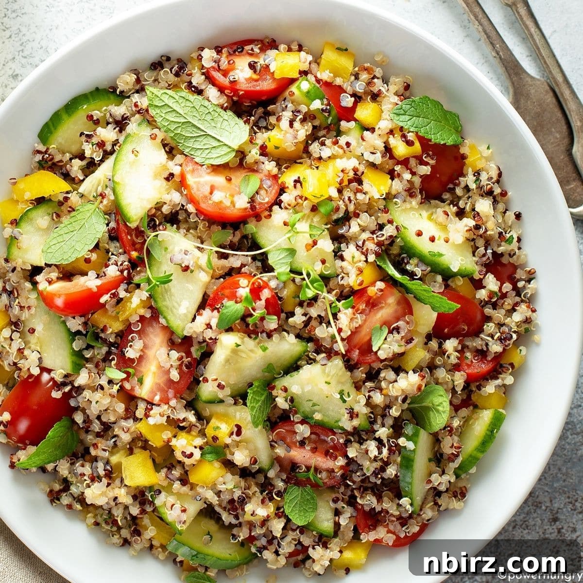 Vibrant Oil-Free Quinoa Bowl 2 A beautifully presented oil-free quinoa salad in a white bowl, garnished with fresh herbs, showcasing its vibrant colors and crunchy textures.