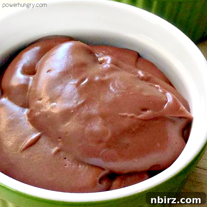 A serving of creamy vegan chocolate avocado pudding in a stylish green and white patterned bowl, ready to be enjoyed.