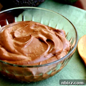 Healthy vegan chocolate avocado pudding in a glass bowl atop a green napkin, ready to be served.