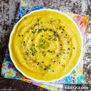 overhead shot of bright yellow split pea dip in a white bowl