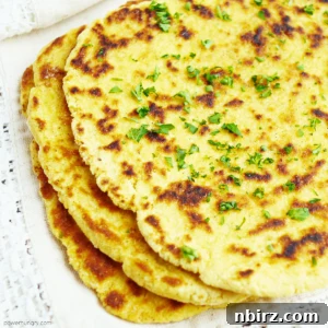Overhead shot of chickpea flour naan with a lace edged napkin alongside