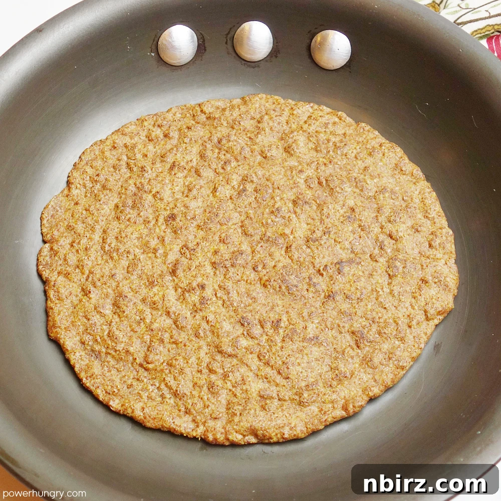 Effortless Keto Flaxseed Wraps 8 A flax tortilla being cooked in a cast iron skillet, showing the slight browning and bubbling that indicates it's ready to flip.