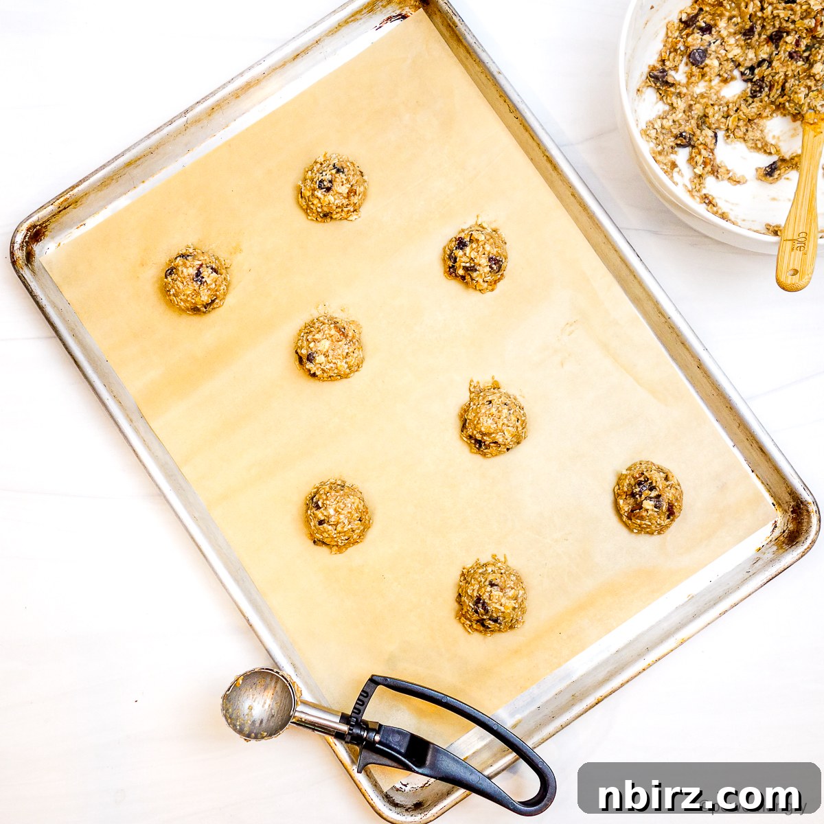 Wholesome Two-Ingredient Banana Oat Cookies 6 Portioned mounds of banana oat cookie dough neatly arranged on a baking sheet, ready for flattening.
