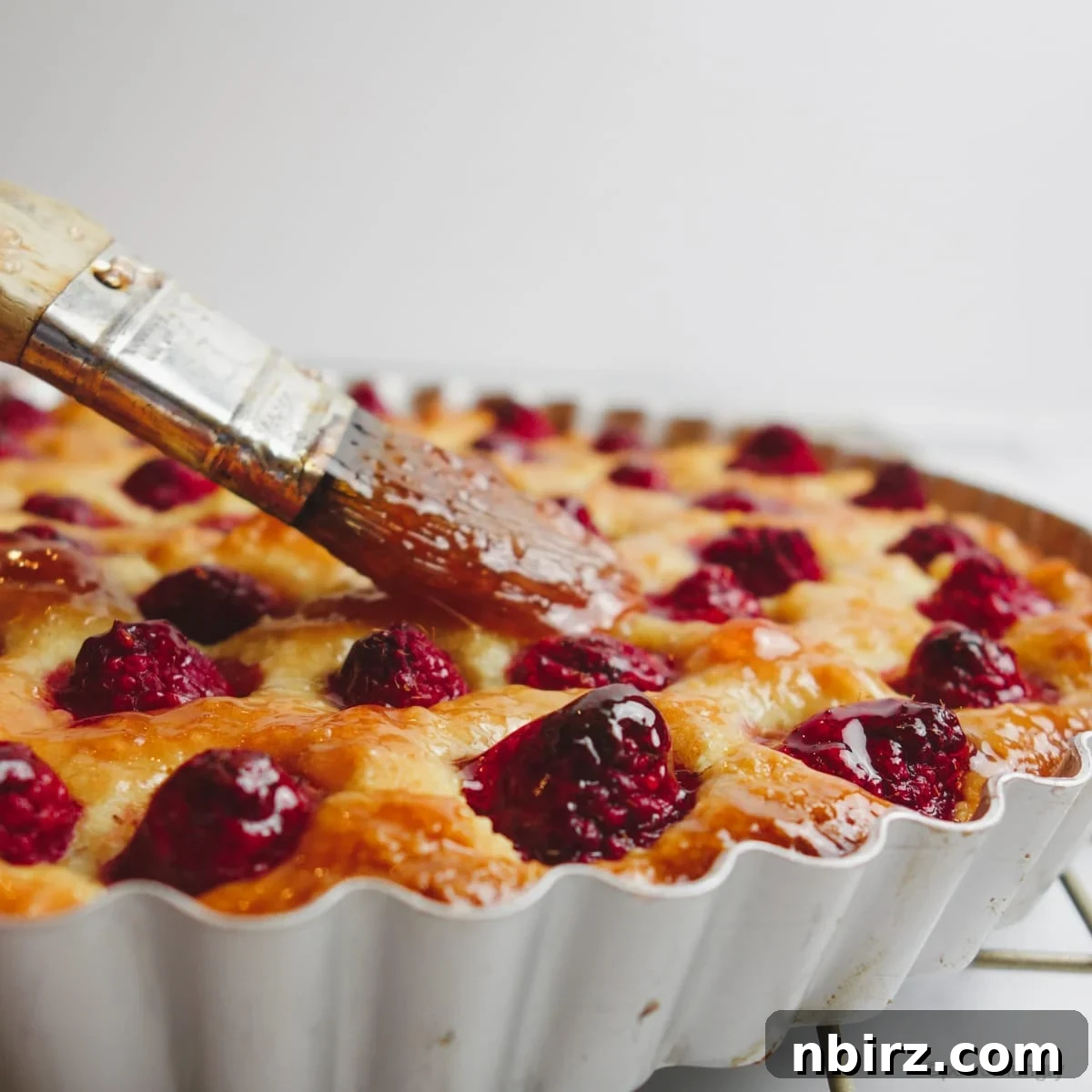 Vegan Raspberry Tart: A Gluten-Free Delight 8 Close up of vegan no-crust raspberry almond tart being brushed with maple syrup
