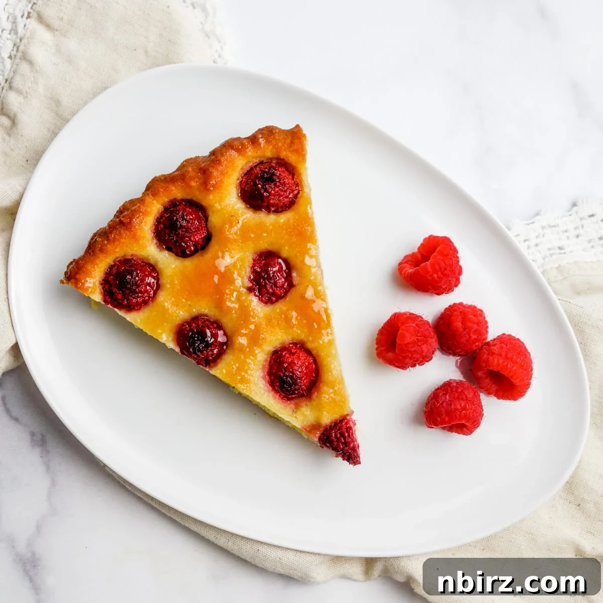 Vegan Raspberry Tart: A Gluten-Free Delight 10 Single slice of vegan no-crust raspberry almond tart on a white plate with fresh raspberries