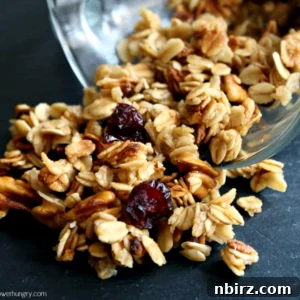Crispy microwave granola spilling out of a mug onto a piece of slate, showcasing its tempting texture.