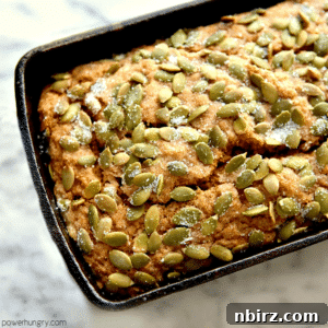 vegan and gluten-free pumpkin bread in a loaf pan atop a marble cutting board