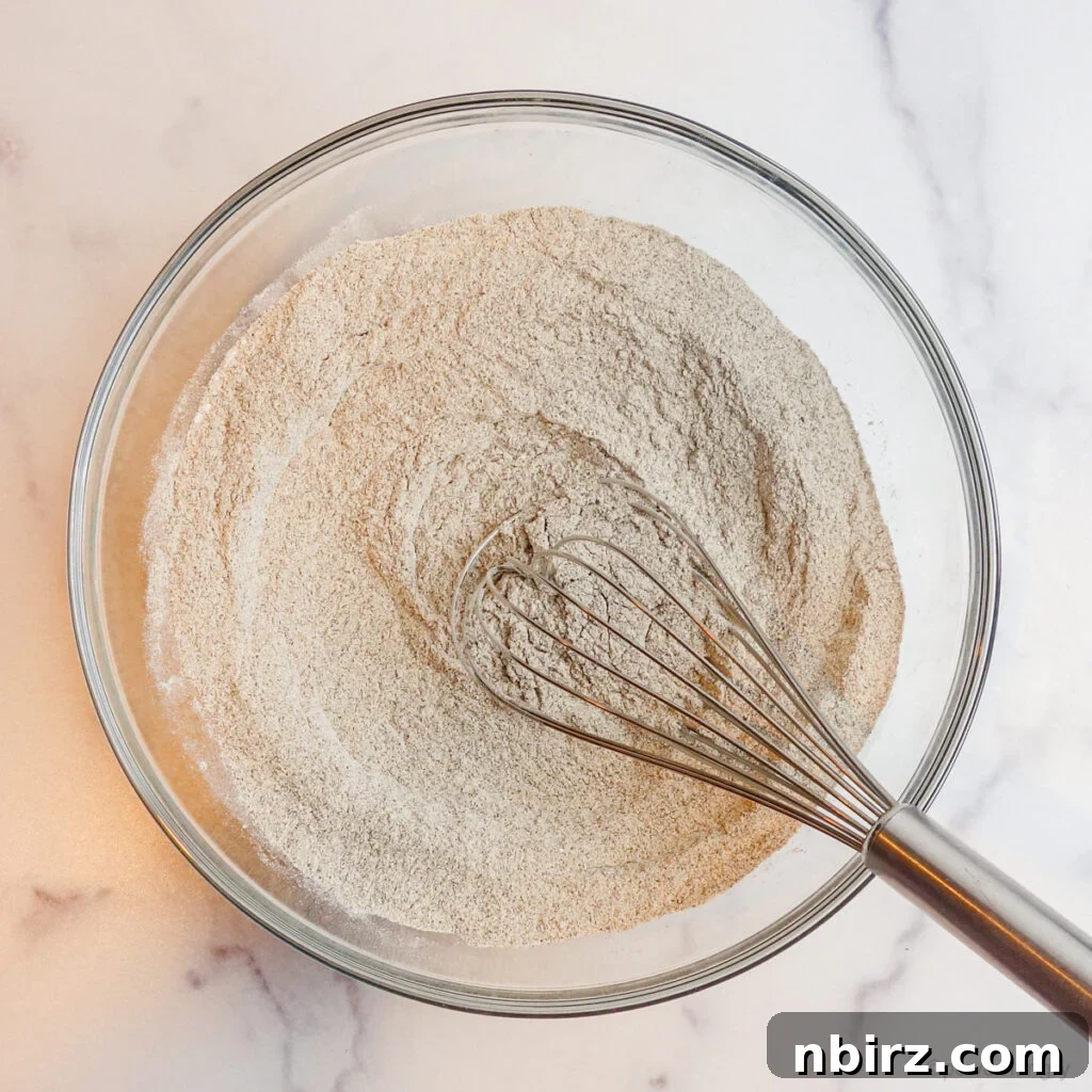 Two-for-Tea Buckwheat Pizza: Simplicity on a Slice 4 A glass bowl containing buckwheat flour, baking powder, and salt, with a metal whisk resting inside.