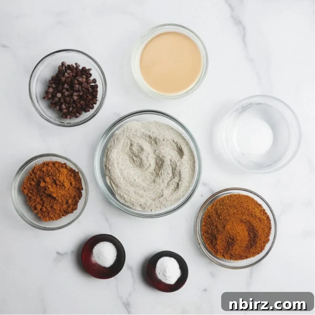 Indulgent Vegan Chocolate Buckwheat Cookies (Gluten-Free Oil-Free) 4 Arrangement of chocolate buckwheat cookie ingredients on a white surface, including buckwheat flour, cocoa powder, tahini, coconut sugar, and chocolate chips.