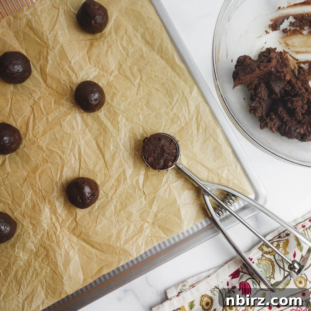 Indulgent Vegan Chocolate Buckwheat Cookies (Gluten-Free Oil-Free) 6 Chocolate buckwheat cookie dough portions rolled into balls and arranged evenly on a parchment-lined baking sheet, ready for the oven.