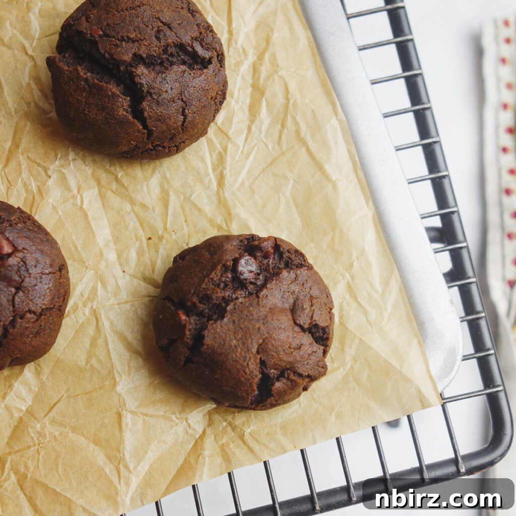 Indulgent Vegan Chocolate Buckwheat Cookies (Gluten-Free Oil-Free) 7 Freshly baked chocolate buckwheat cookies on a baking sheet, with slight cracks on top and a rich brown color.