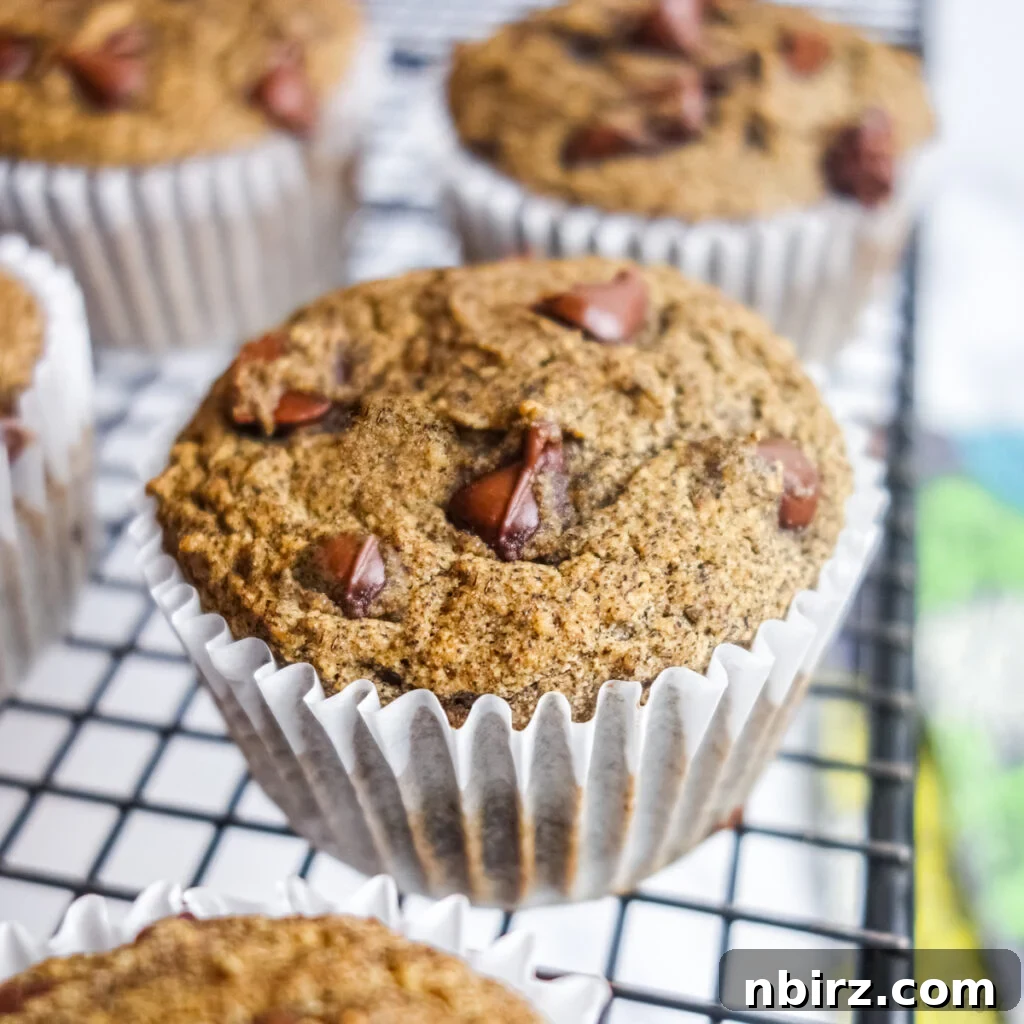 Freshly baked vegan gluten-free buckwheat muffins in white paper liners on a black cooling rack, showcasing their golden-brown tops and inviting texture.