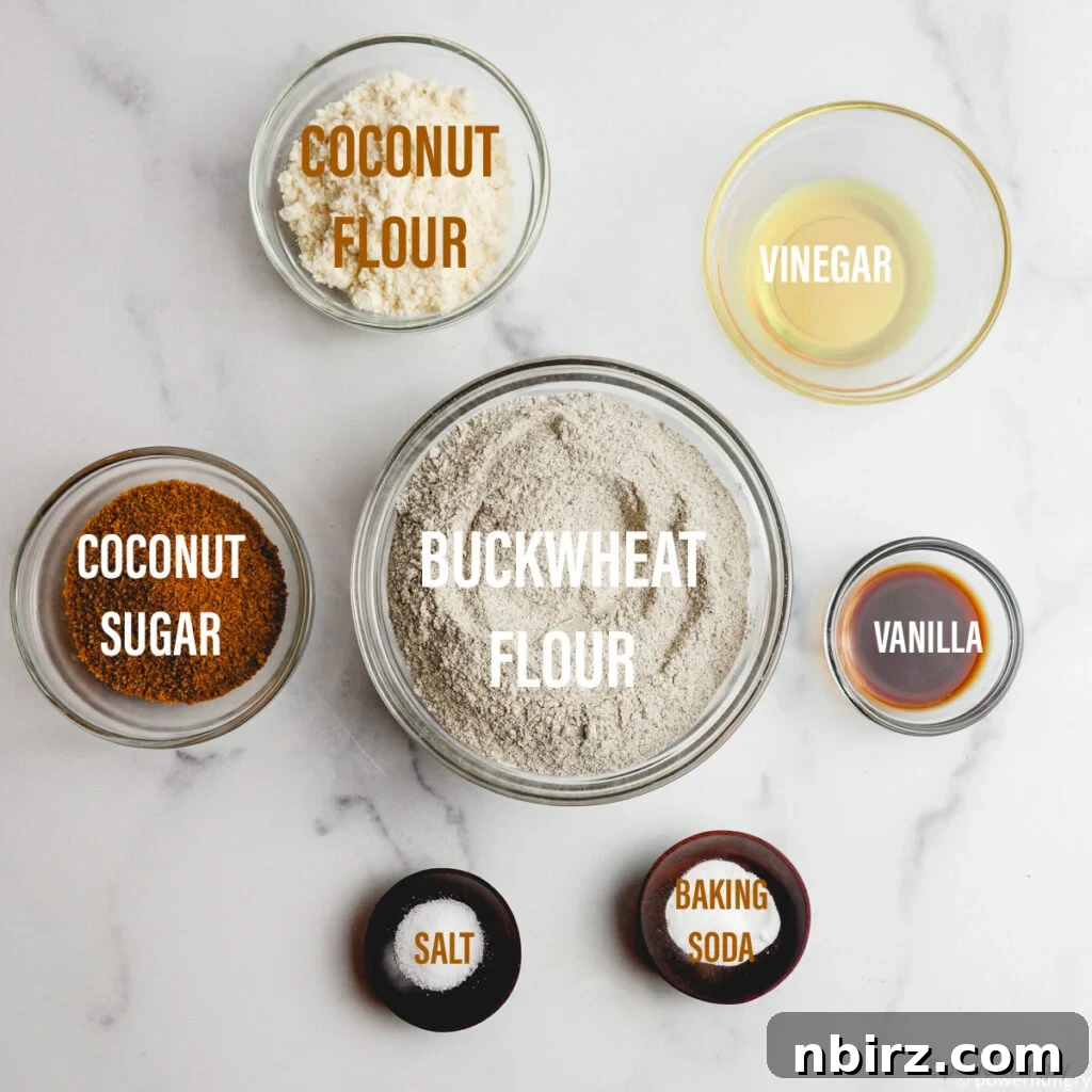 Overhead shot of all the dry and wet ingredients for buckwheat muffins laid out in small bowls on a kitchen surface.