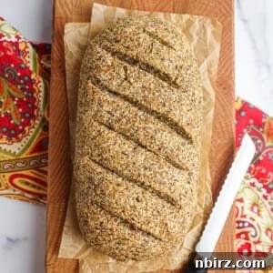 Wholesome Vegan Coconut Flour Flax Bread 2 Overhead shot of a rustic loaf of coconut flour flax bread on a wooden cutting board with a colorful napkin underneath
