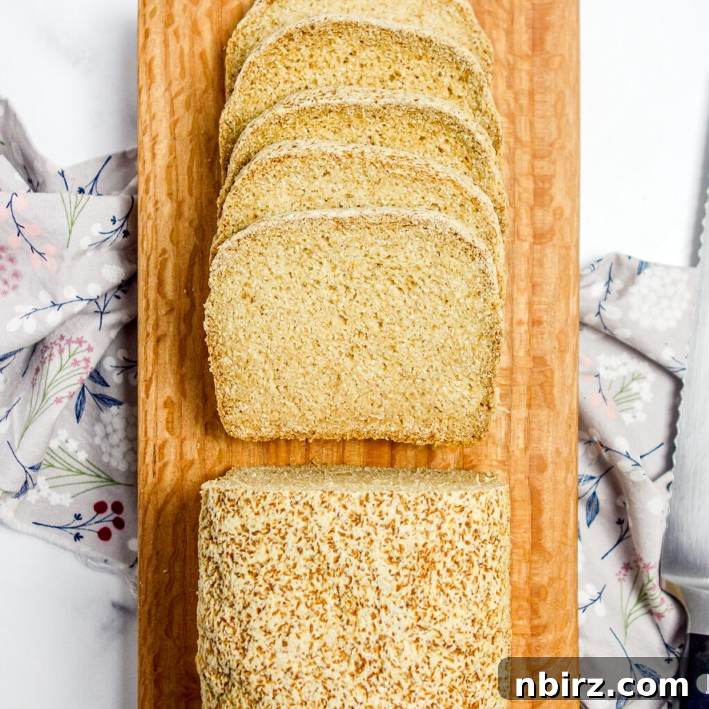 A freshly baked sandwich bread, partially sliced and resting on a wooden cutting board, inviting a taste.