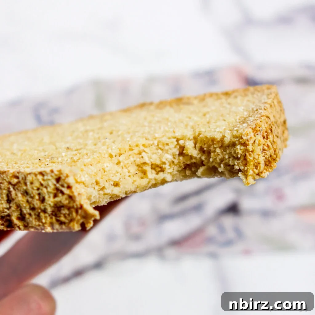 A perfectly sliced piece of vegan coconut flour bread with a bite taken out, showing its fine texture.