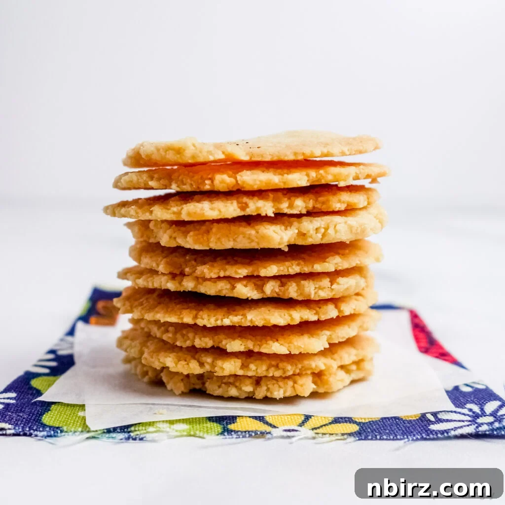 A beautifully arranged stack of golden-brown almond flour crackers resting on a blue floral napkin, highlighting their crisp texture.
