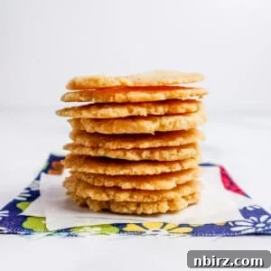 A stack of golden-brown almond flour crackers on a blue floral napkin, representing the finished recipe.