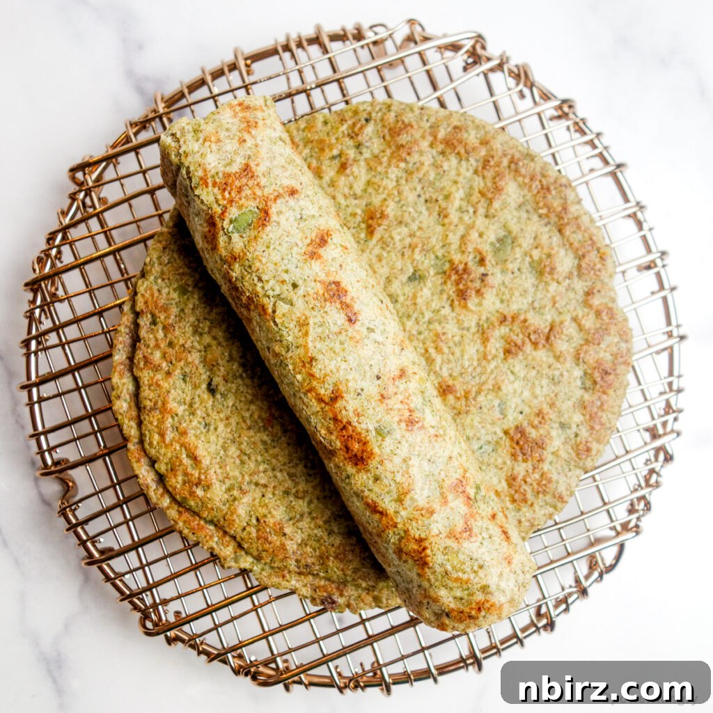 Two-Ingredient Protein-Packed Pumpkin Seed Tortillas 10 A stack of golden pepita tortillas, with one perfectly rolled tortilla placed invitingly on top, showcasing its flexibility.