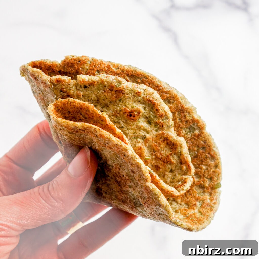 Two-Ingredient Protein-Packed Pumpkin Seed Tortillas 12 A hand gently holding a quartered pepita tortilla, ready to be enjoyed as a snack or scoop.