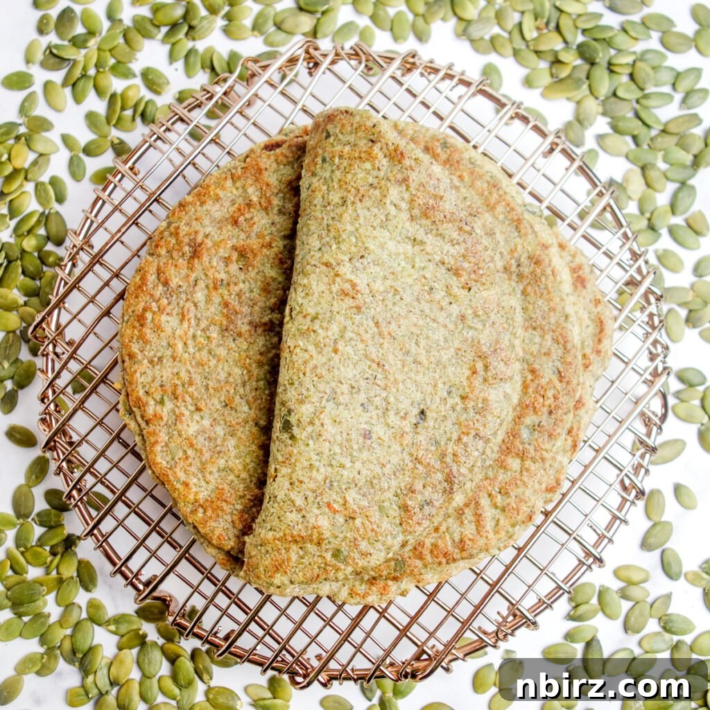 Two-Ingredient Protein-Packed Pumpkin Seed Tortillas 3 An inviting overhead shot of freshly made pepita tortillas on a cooling rack, surrounded by raw green pumpkin seeds, highlighting their natural origin.