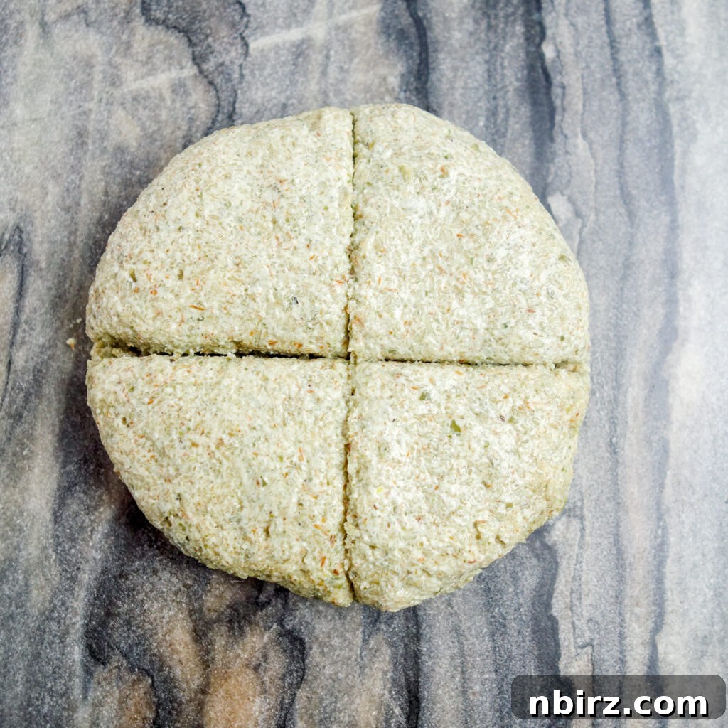Two-Ingredient Protein-Packed Pumpkin Seed Tortillas 6 A perfectly formed disk of pepita tortilla dough resting on a grey marble cutting board, precisely divided into four equal quarters.
