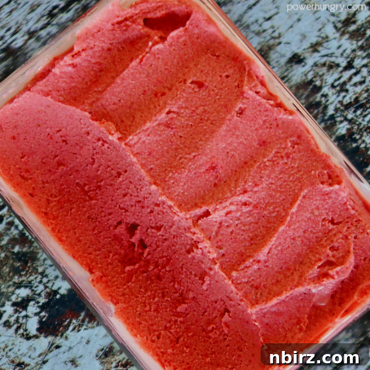 No-Fuss Two-Ingredient Strawberry Sorbet 4 Freezer-safe container brimming with firm, vibrant strawberry sorbet, ready to be served.