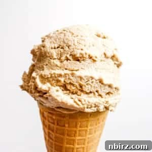 A scoop of sunflower seed vanilla ice cream on a sugar cone, showcasing its creamy texture.