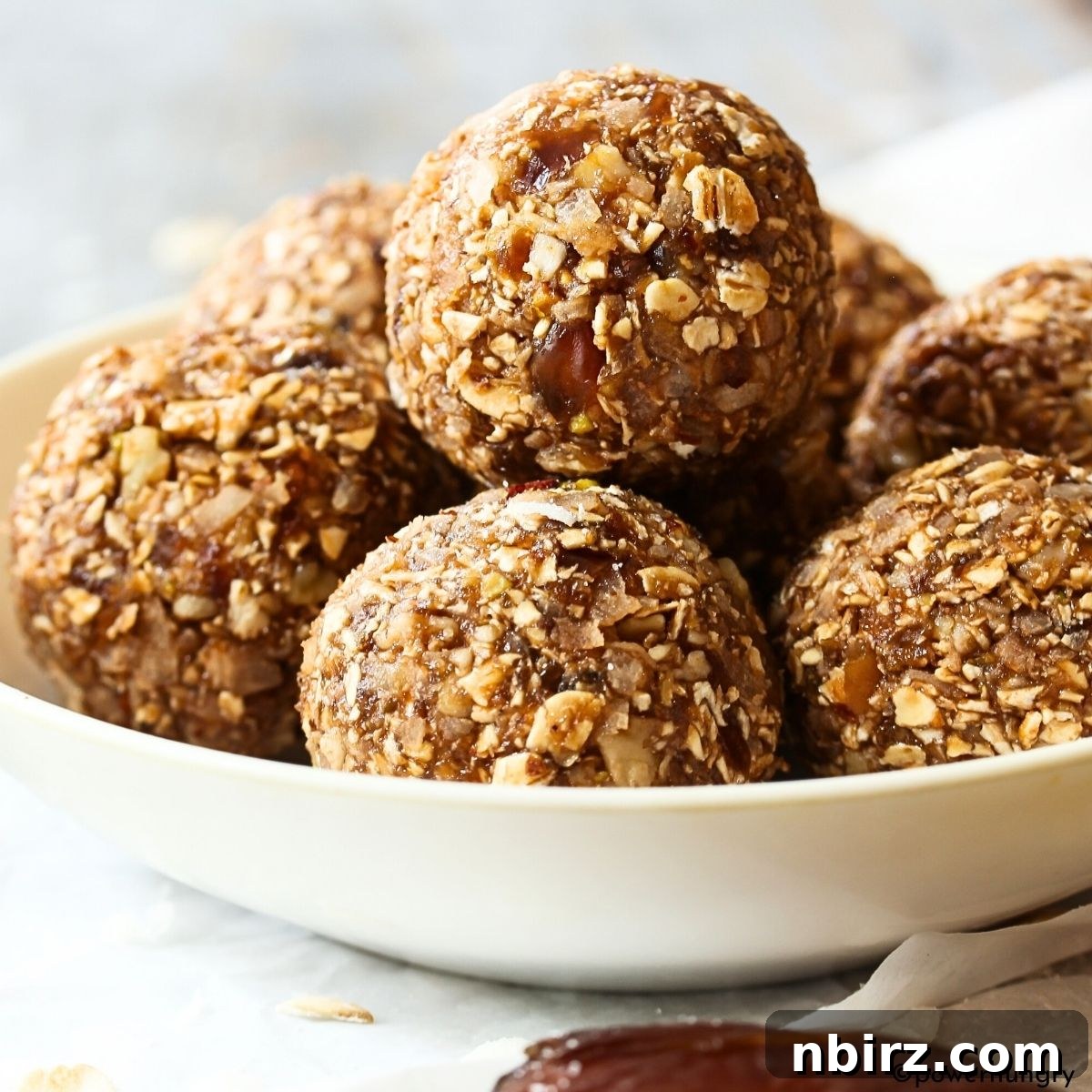 Festive Gingerbread Bliss Balls 4 Gingerbread energy balls presented beautifully in a white ceramic bowl, highlighting their warm hues.