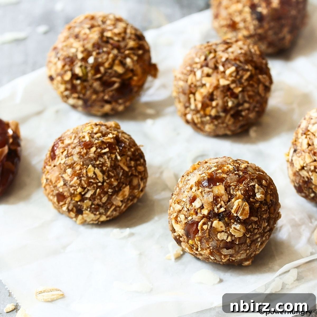 Festive Gingerbread Bliss Balls 5 Gingerbread energy balls neatly arranged on a piece of white parchment paper, ready for chilling.