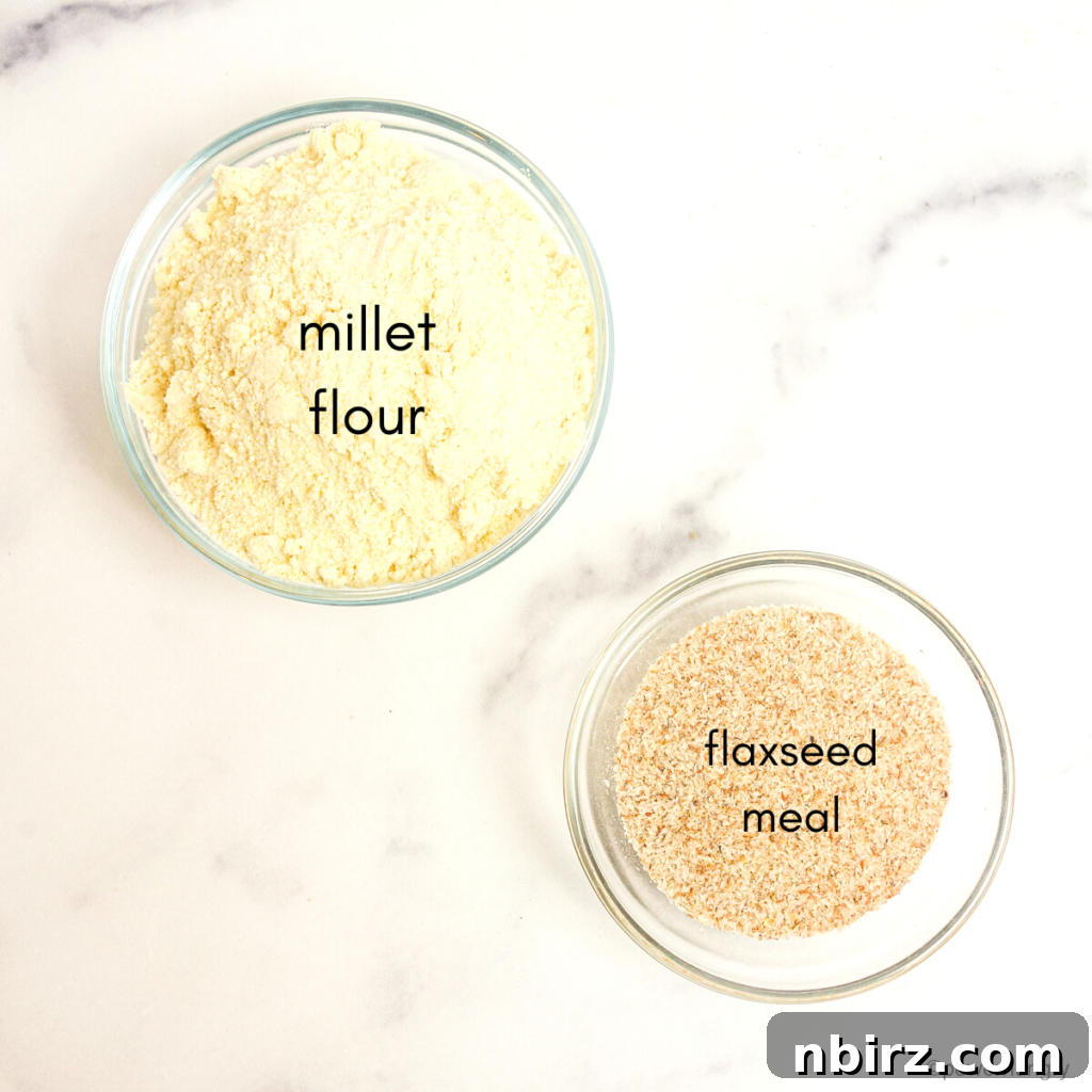A close-up, overhead shot of two glass bowls, one filled with fine millet flour and the other with golden flaxseed meal, the two core ingredients for the tortillas.