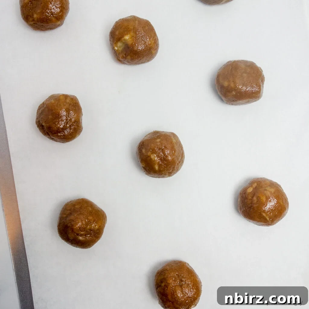 Effortless Two-Ingredient Vegan Gluten-Free Oil-Free Peanut Butter Banana Cookies 7 cookie dough balls on a parchment lined baking sheet
