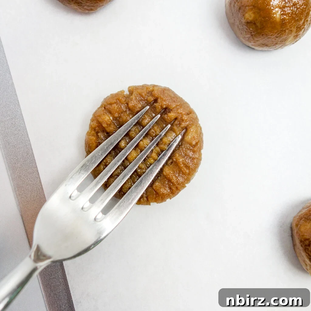 Effortless Two-Ingredient Vegan Gluten-Free Oil-Free Peanut Butter Banana Cookies 8 a peanut butter banana cookie getting flattened and marked with a fork