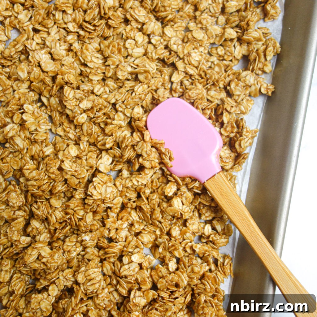 Healthy 3-Ingredient Oil-Free Peanut Butter Granola 4 granola mixture spread on a parchment lined baking sheet