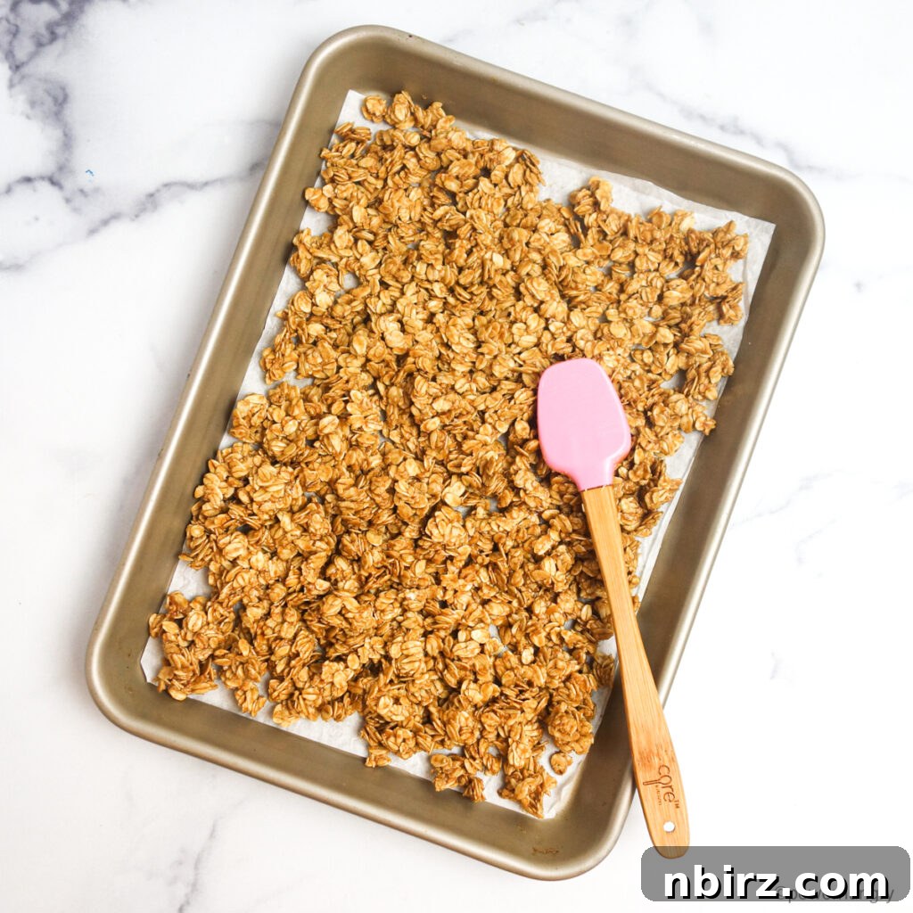 Healthy 3-Ingredient Oil-Free Peanut Butter Granola 5 granola tamped down with a pink spatula