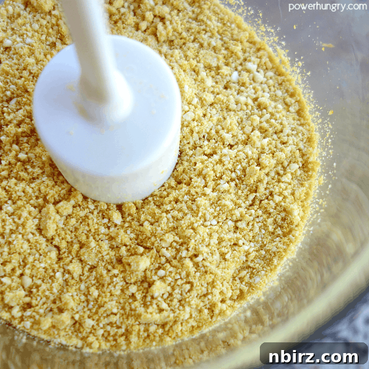 The food processor filled with finely ground DIY vegan parmesan cheese, demonstrating its perfect crumbly texture.