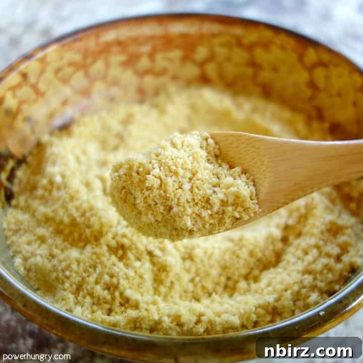 A close-up view of a spoonful of freshly made DIY vegan Parmesan cheese, showcasing its delightful, fine texture.
