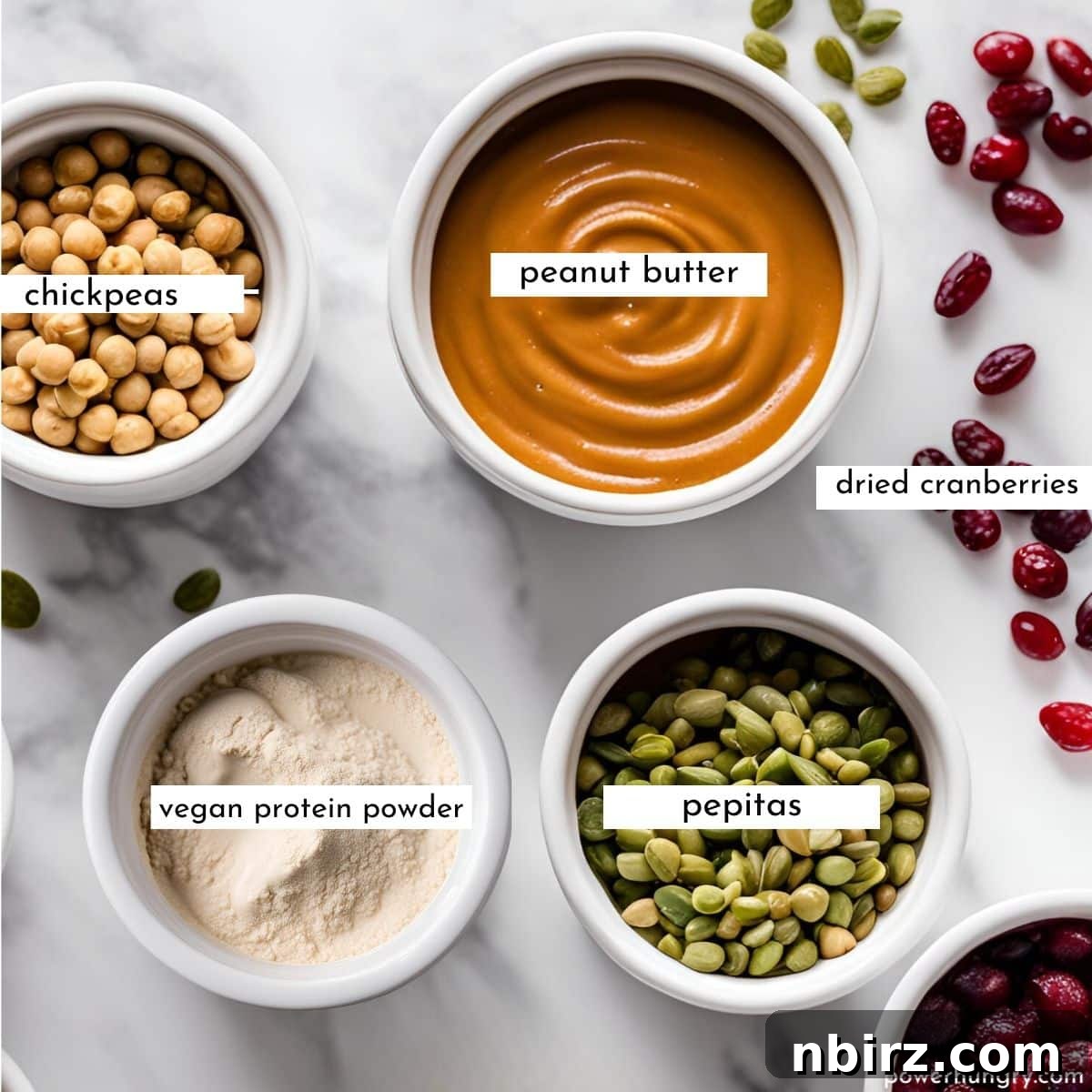 No Bake Grain Free Vegan Chickpea Protein Bites 4 Overhead shot of ramekins filled with ingredients for chickpea protein bars: chickpeas, dates, peanut butter, protein powder, pepitas, and cranberries.